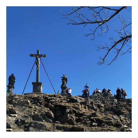 Menschengruppe und ein Kreuz auf einem Berg